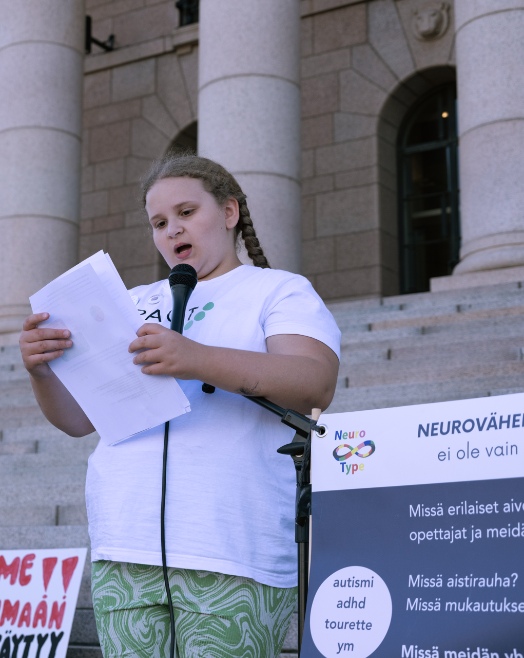 Nuori nainen pitää puhetta eduskuntatalon edessä.