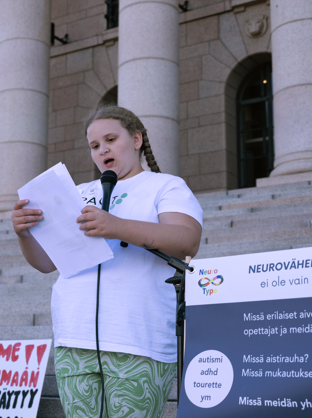 Nuori nainen pitää puhetta eduskuntatalon edessä.