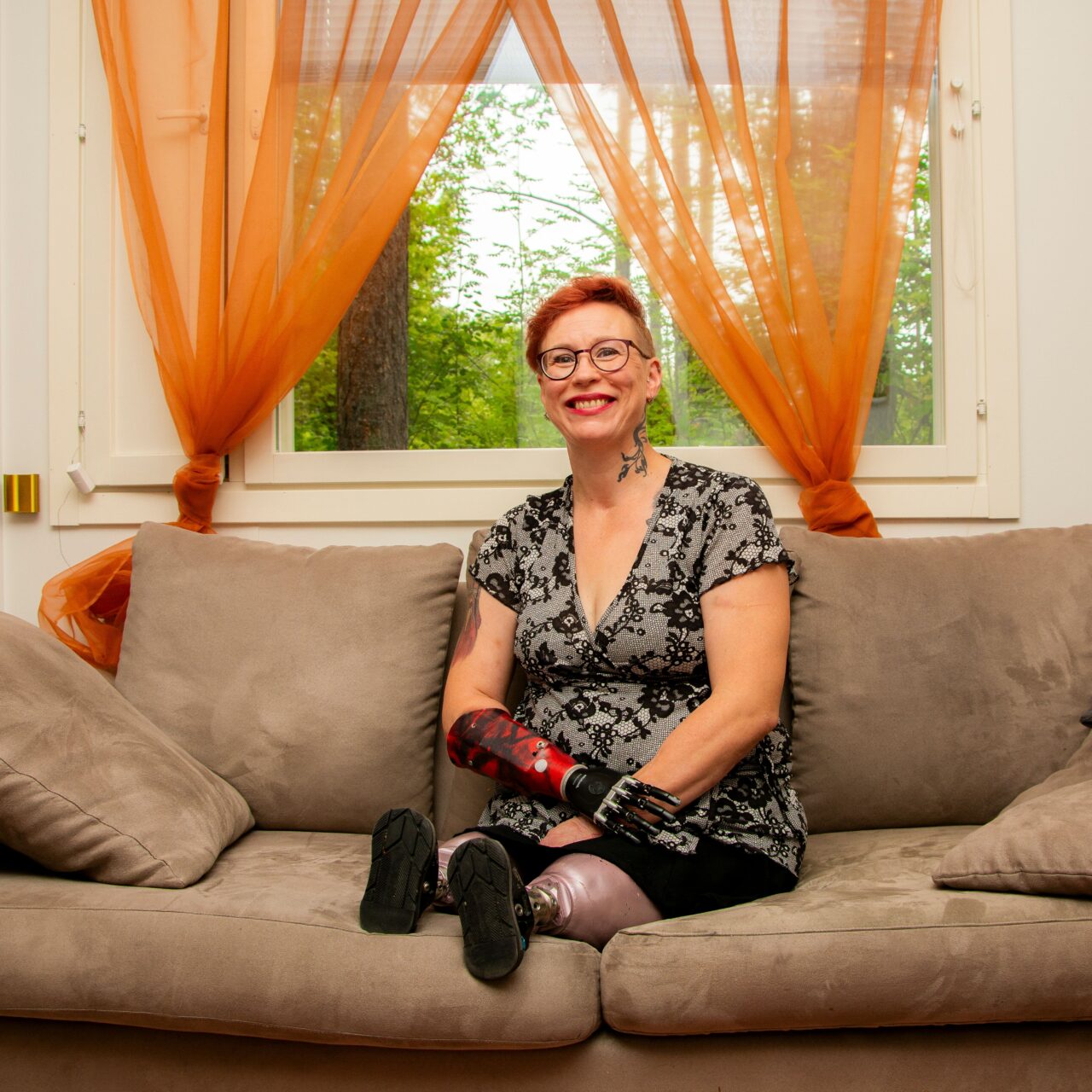 Proteeseja käyttävä nainen istuu sohvalla.