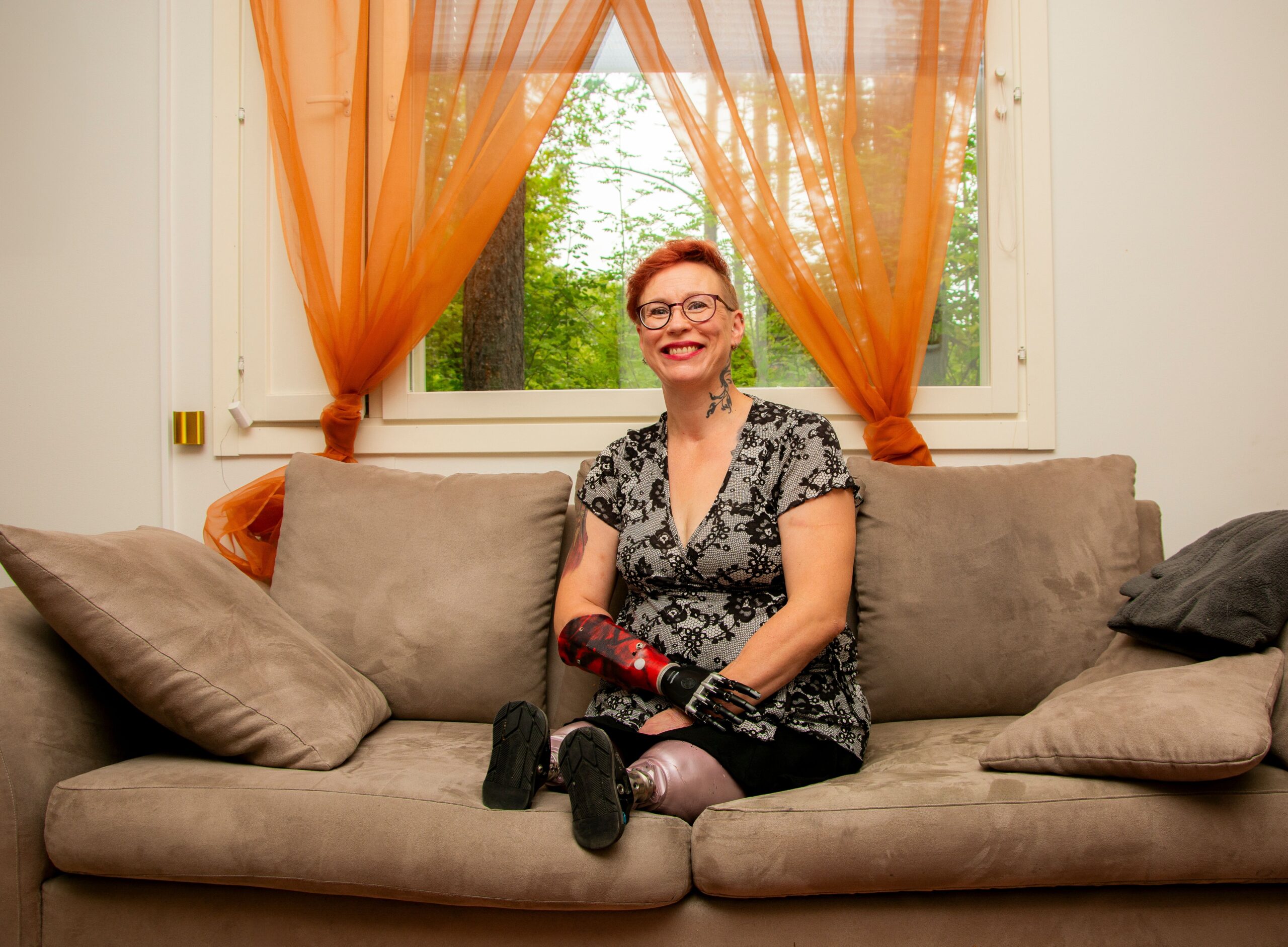 Proteeseja käyttävä nainen istuu sohvalla.