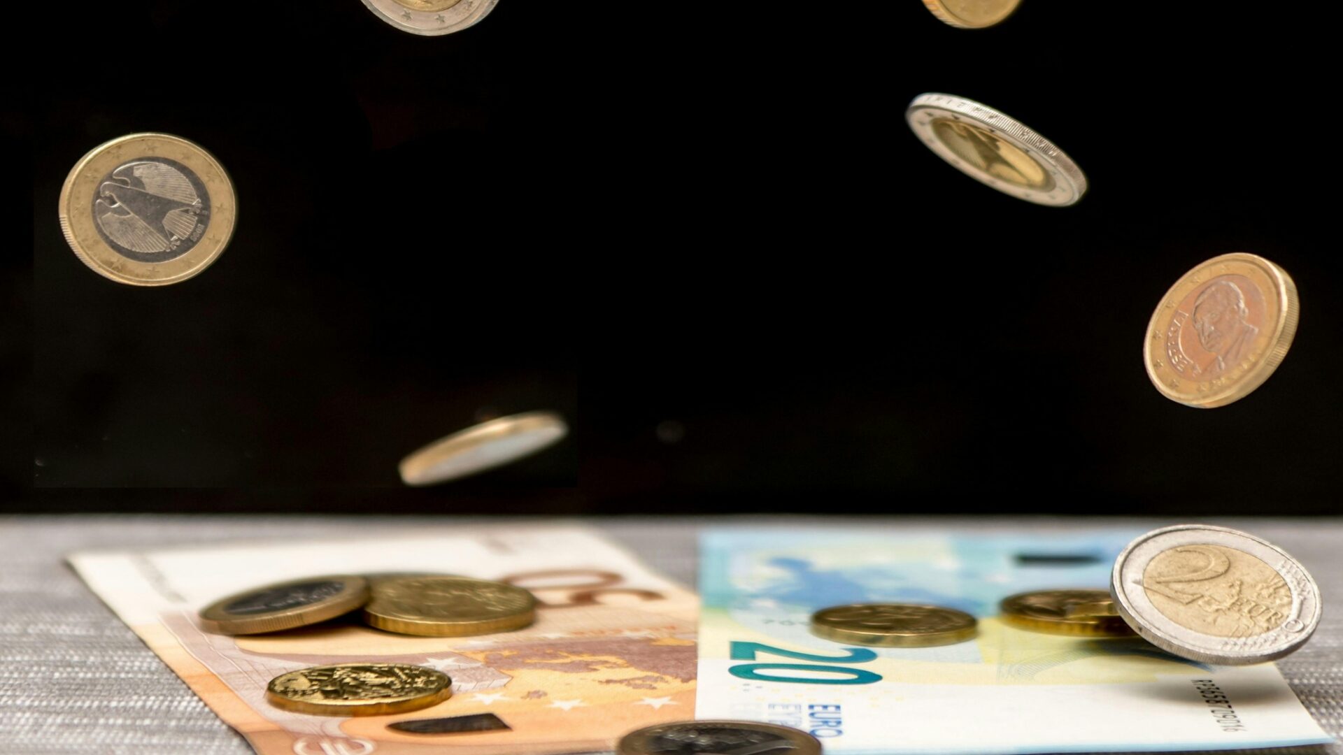 Eurokolikoita putoilee 20 ja 50 euron seteleiden päälle.