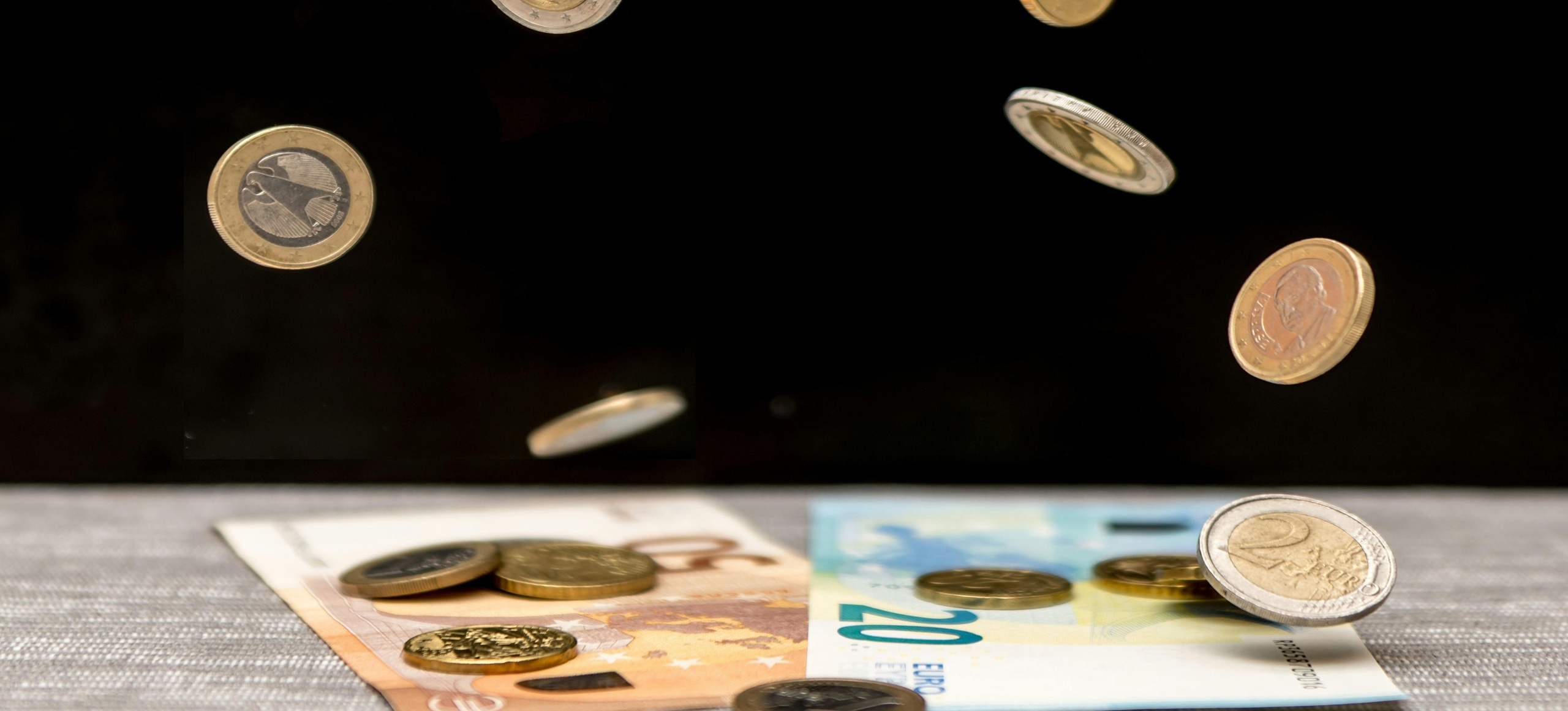Eurokolikoita putoilee 20 ja 50 euron seteleiden päälle.