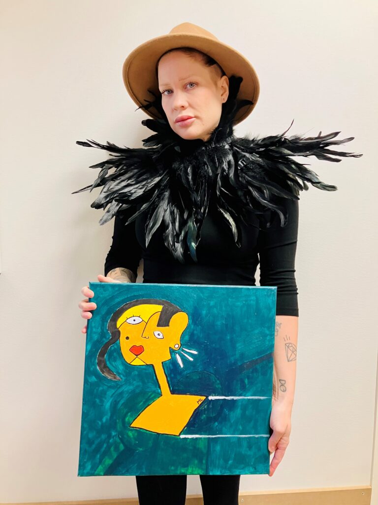Nainen pitää taulua käsissään.