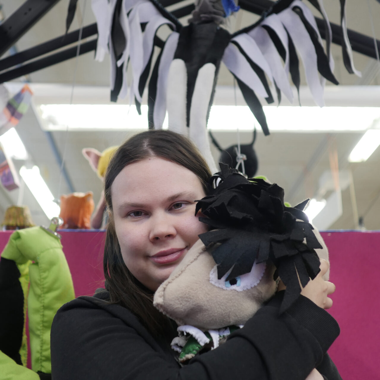 Nainen pitää sylissään virkattua pehmolelua.