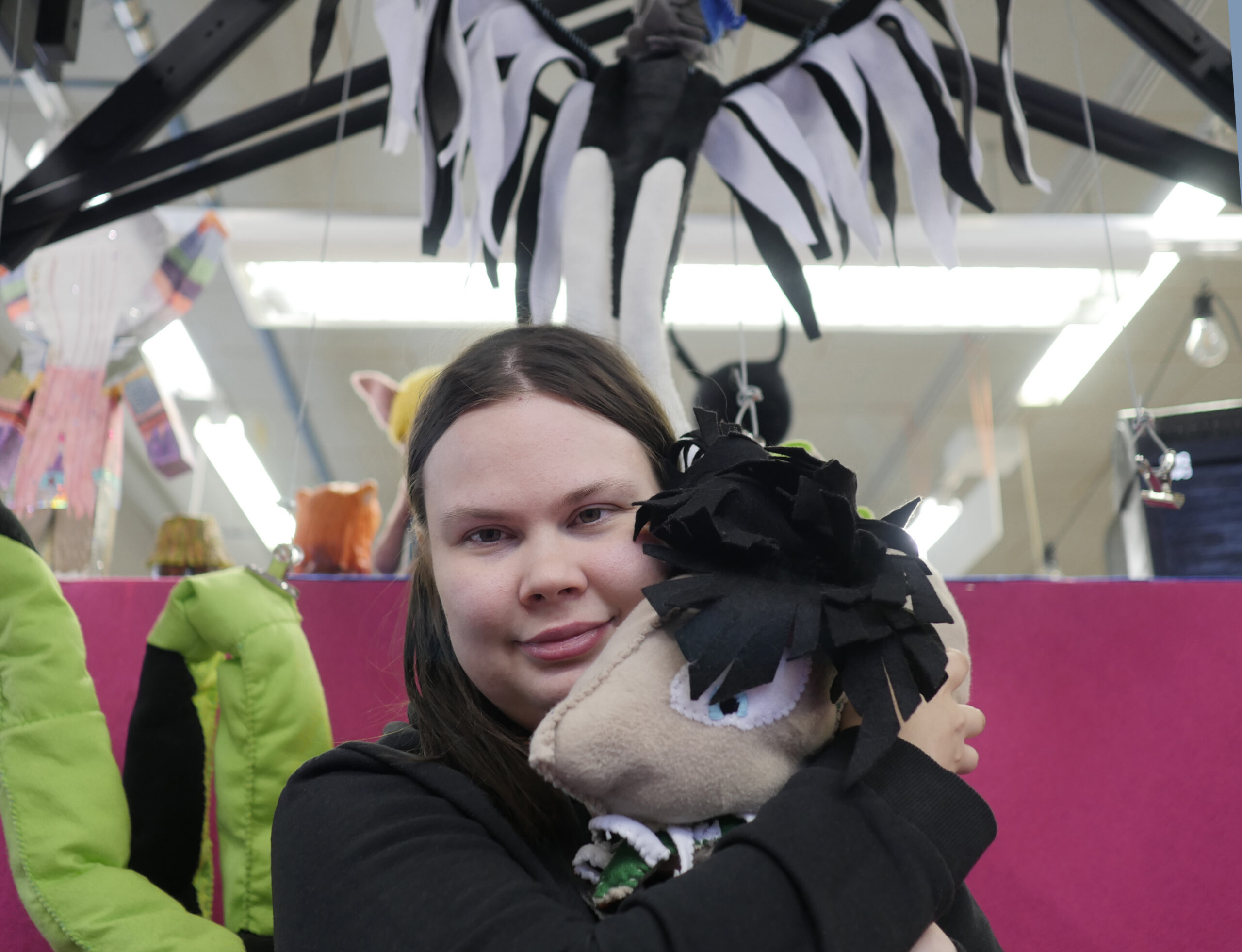 Nainen pitää sylissään virkattua pehmolelua.