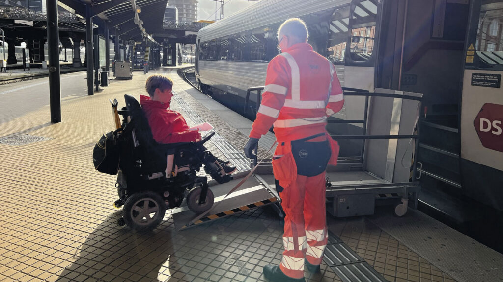 Pyörätuolissa istuva Sanna Kalmari siirtymässä junaan liuskaa pitkin.