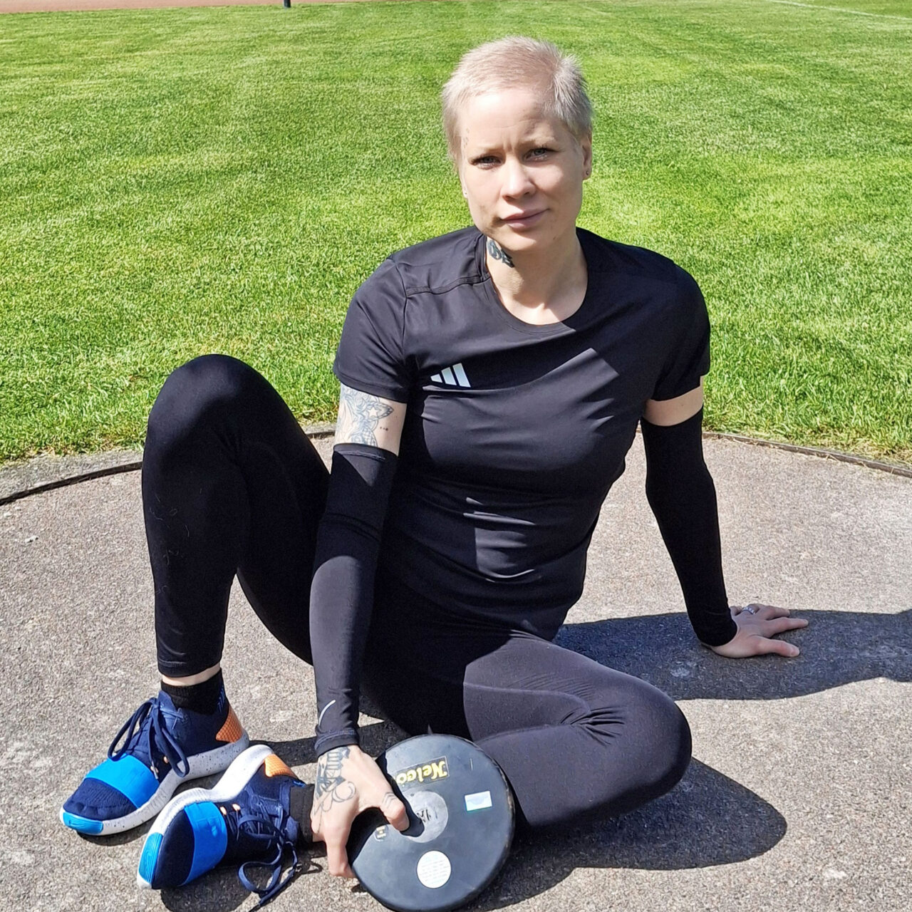 Maaria Laiho istuu kiekon kanssa kiekonheittokehässä.
